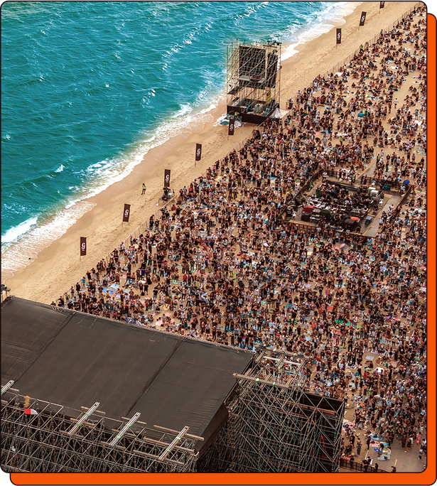 ภาพมุมสูงของเวทีและผู้คนในงานเทศกาลดนตรี Rock on the Beach ริมชายหาด